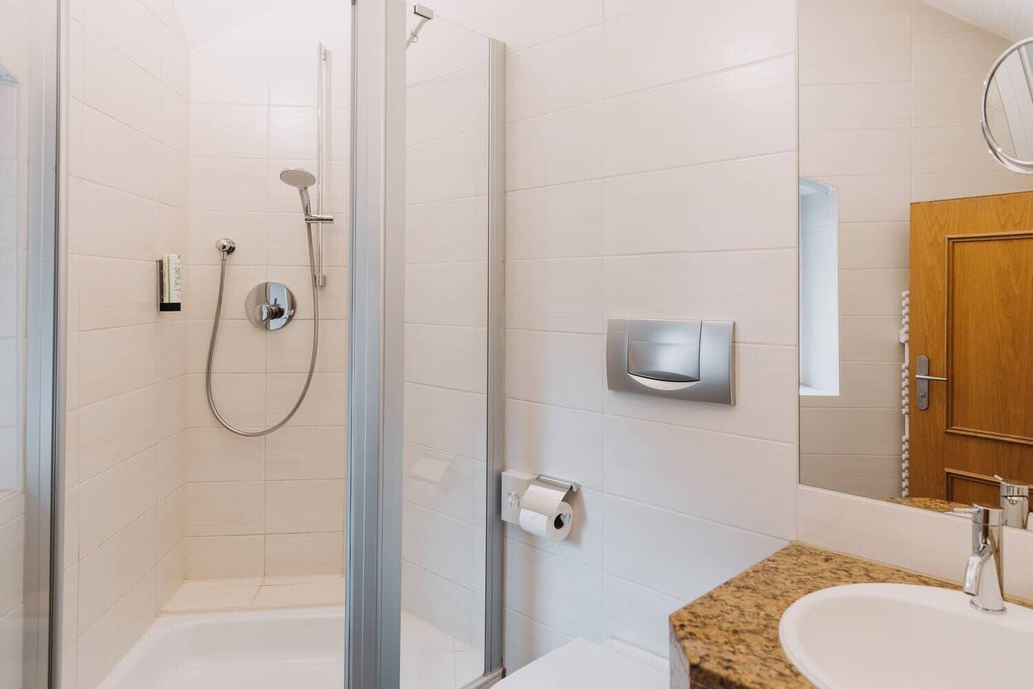 Badezimmer mit moderner Dusche im Hotel, ausgestattet mit hochwertigen Armaturen und hellem, freundlichem Design.