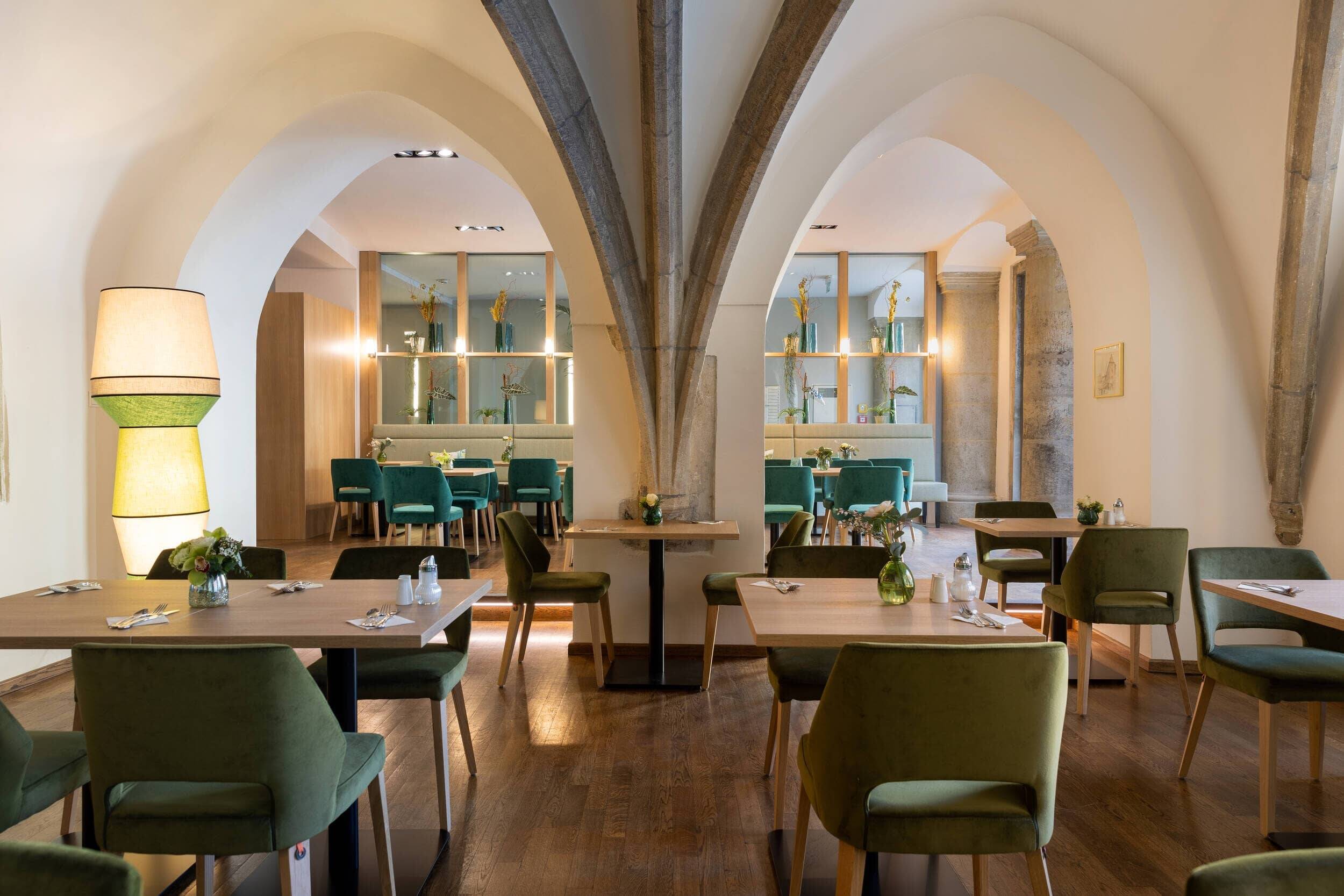 Modernes Restaurant mit grünen Stühlen und Holzstühlen, ideal für Familienessen und entspannte Abende im Hotel.