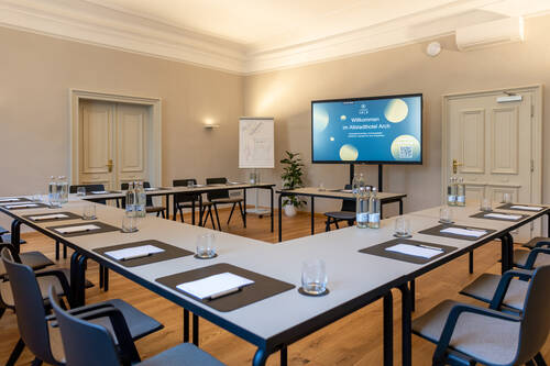 Modern ausgestatteter Tagungsraum im Altstadthotel Arch, ideal für Meetings, mit Tischen, Stühlen und Präsentationstechnik.