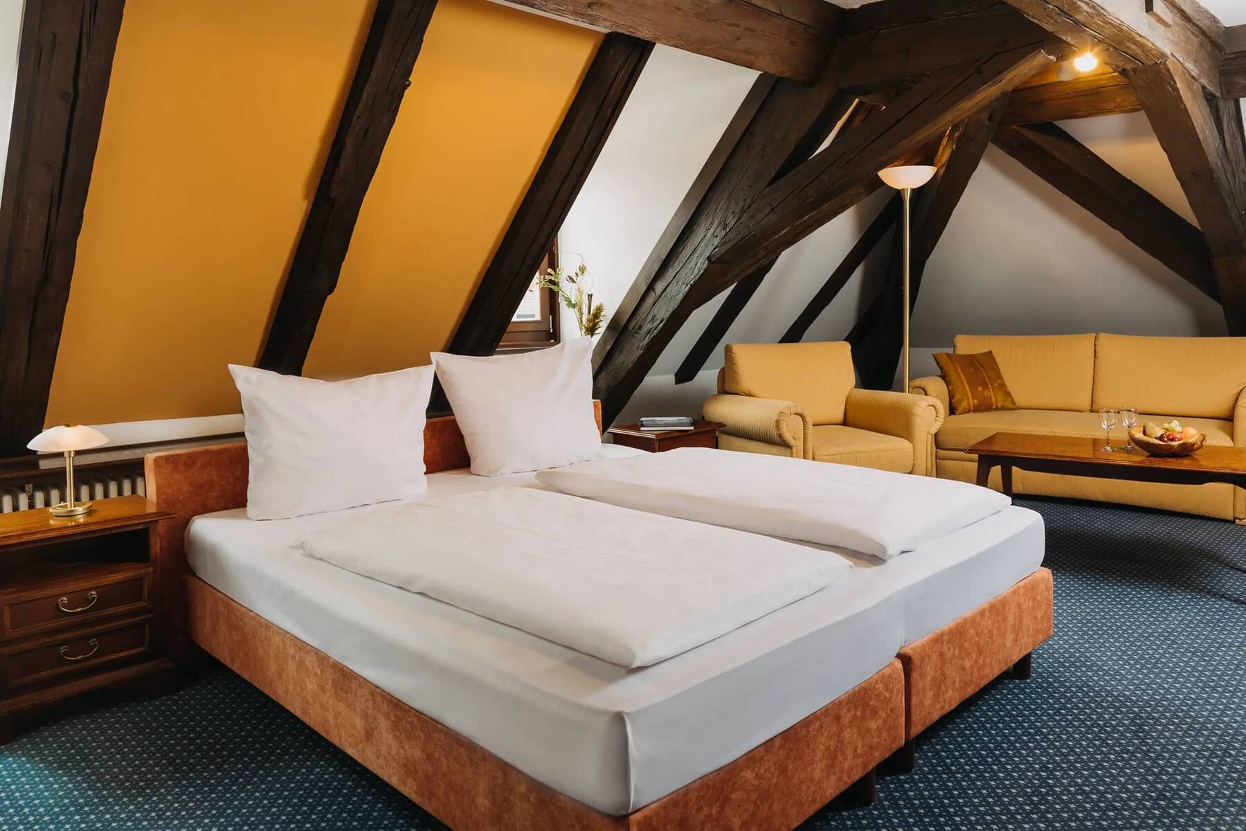 Doppelzimmer im Hotel mit Holzvertäfelung, zwei Betten und einer gemütlichen Sitzecke für erholsame Nächte während des Urlaubs.