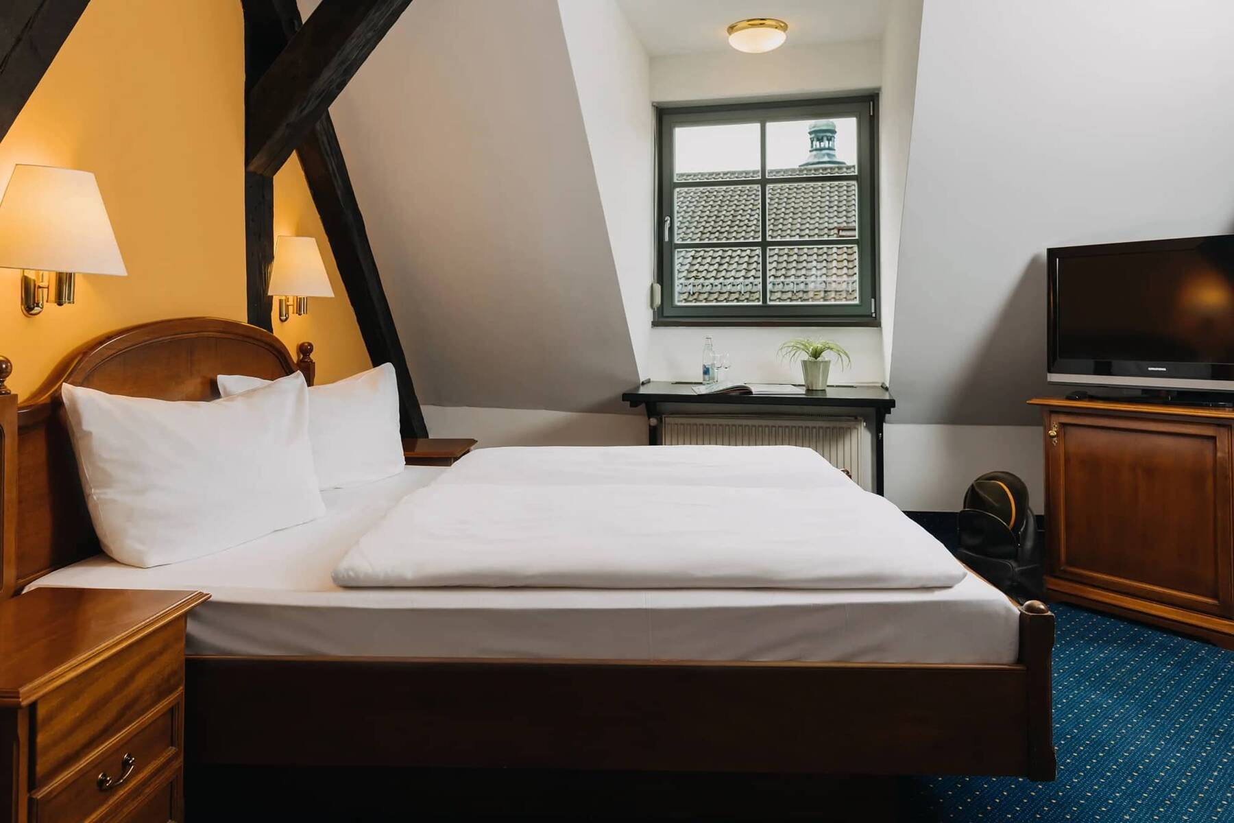 Ein gemütliches Hotelzimmer mit einem Doppelbett, Fernseher und Fenster, ideal für einen entspannten Familienurlaub.