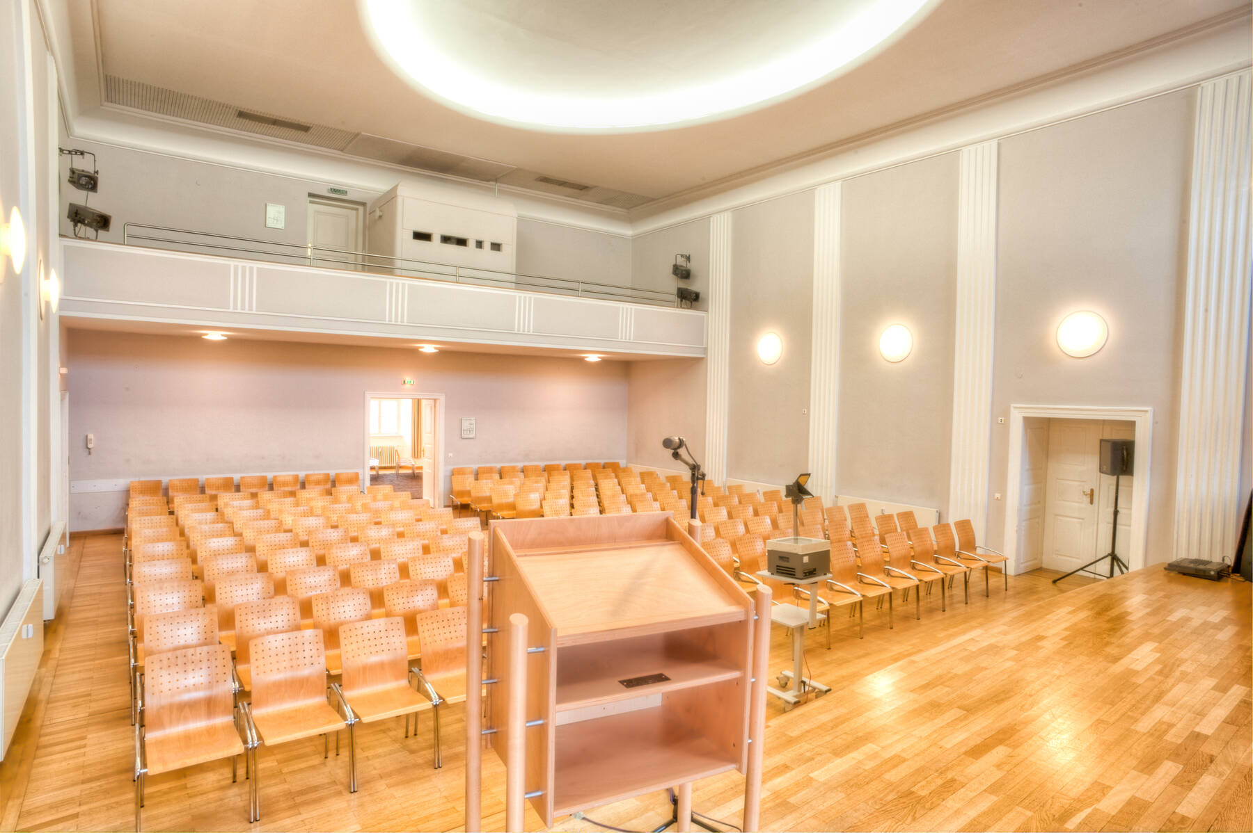 Ein Konferenzraum im Eventzentrum mit Holzfußboden, Reihen von Stühlen und einem Podium für Präsentationen und Events.