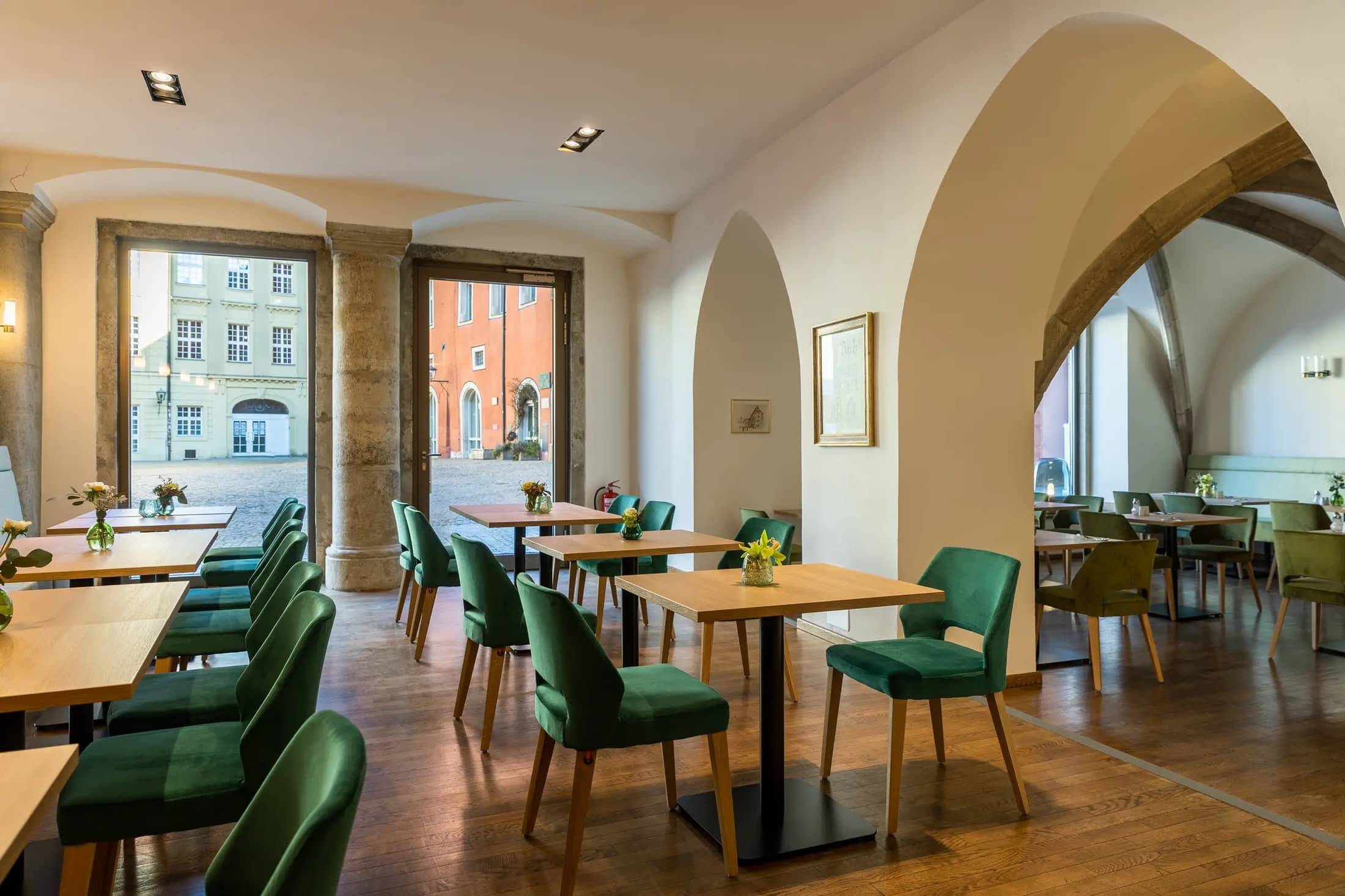 Gemütliches Café mit modernen Holztischen und grünen Stühlen, ideal für entspannte Momente während des Stadtbesuchs.