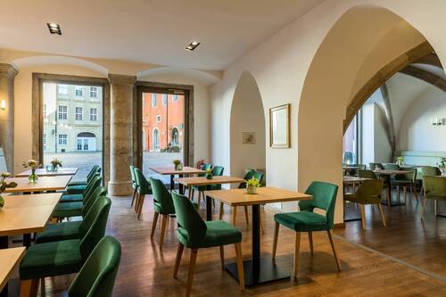 Gemütliches Café mit modernen Holztischen und grünen Stühlen, ideal für entspannte Momente während des Stadtbesuchs.