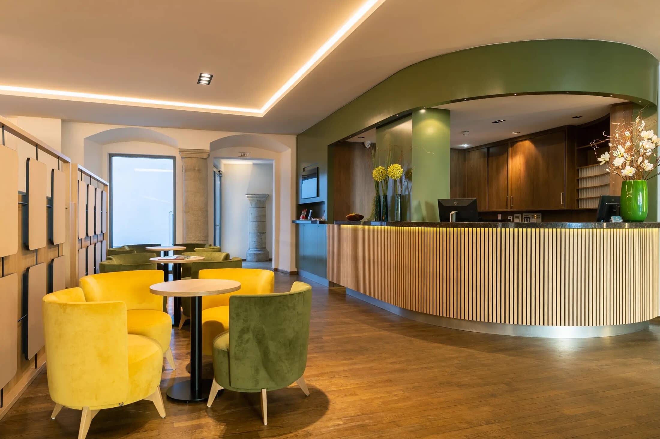 Die moderne Hotellobby mit gelben und grünen Sesseln lädt zum Verweilen ein, ideal für einen entspannten Aufenthalt im Hotel.