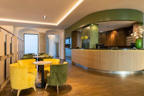 Die moderne Hotellobby mit gelben und grünen Sesseln lädt zum Verweilen ein, ideal für einen entspannten Aufenthalt im Hotel.