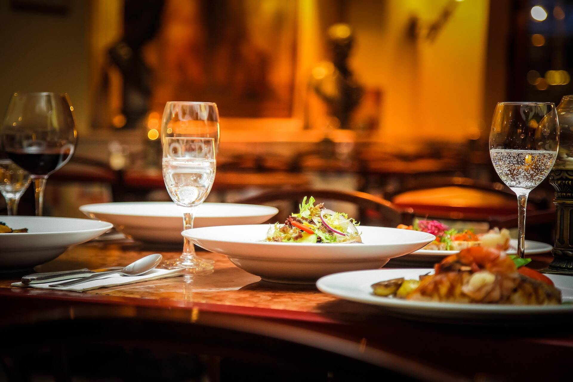 Elegantes Restaurant mit Tischgedeck, feinen Weinen und frisch zubereiteten Salaten für ein genussvolles Abendessen.