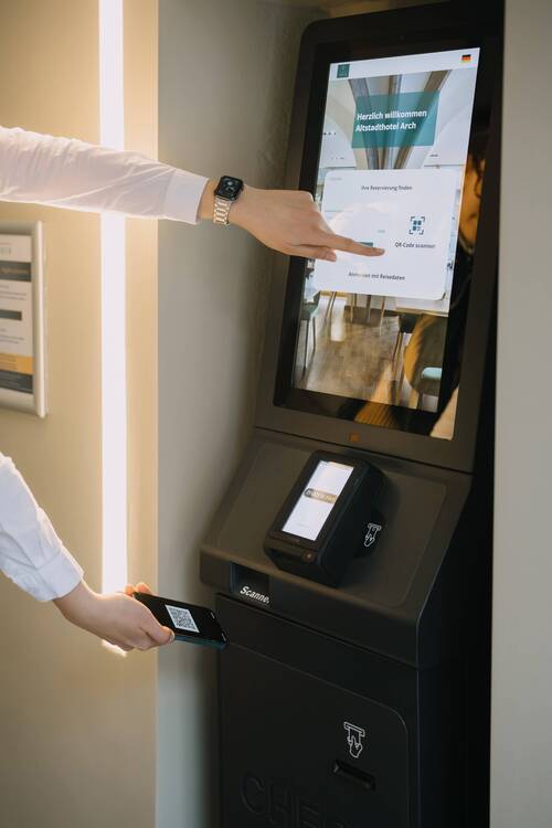 Hand entnimmt eine Zimmerkarte aus dem digitalen Check-in-Automaten im Altstadthotel Arch Regensburg – Self-Check-in rund um die Uhr