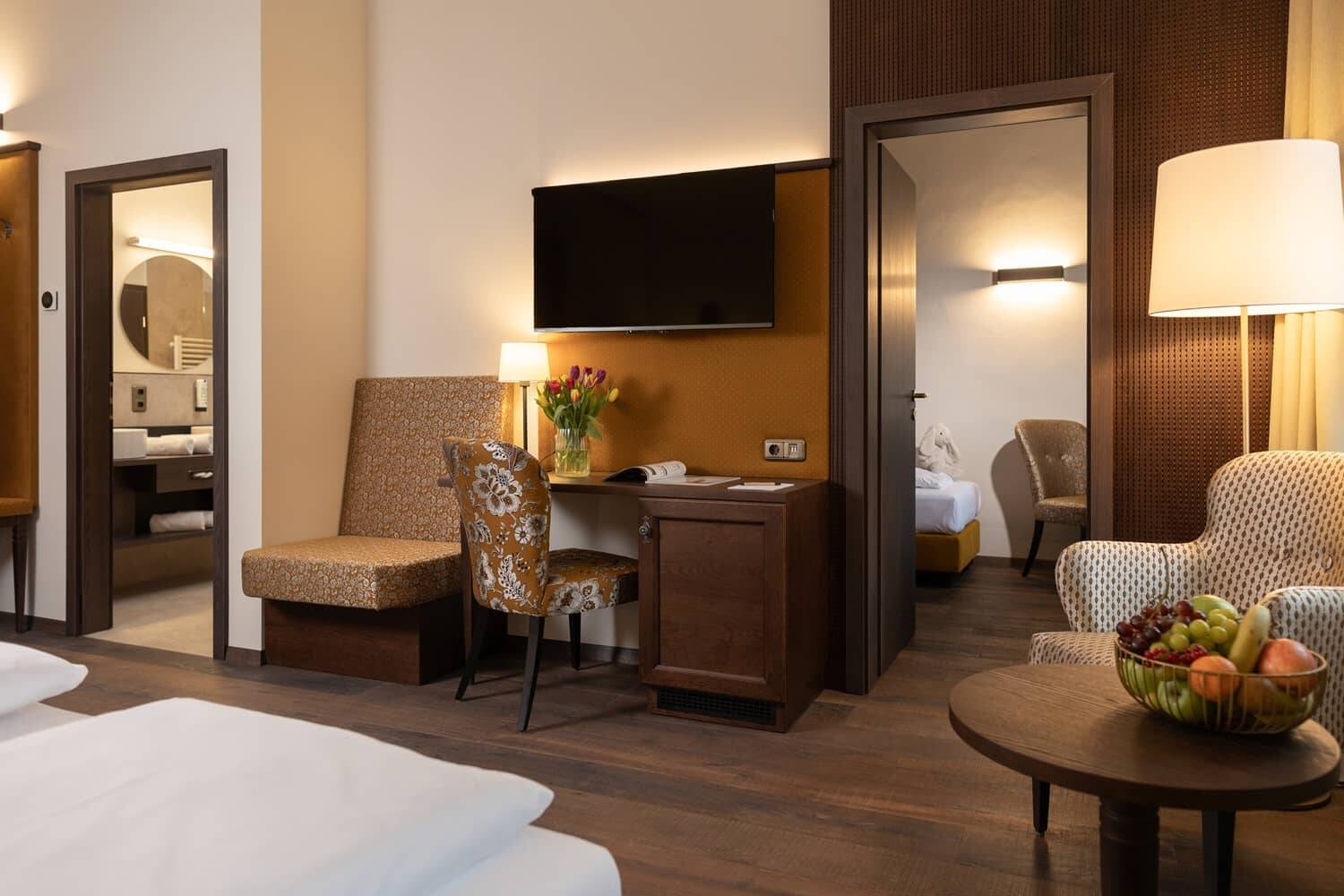Modernes Hotelzimmer mit Sitzecke und Schreibtisch, ideal für einen komfortablen Familienurlaub im Hotel.