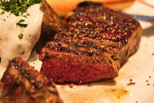 Ein perfekt gegrilltes Steak mit Kräutern und einer cremigen Beilage im Restaurant, ideal für Fleischliebhaber.