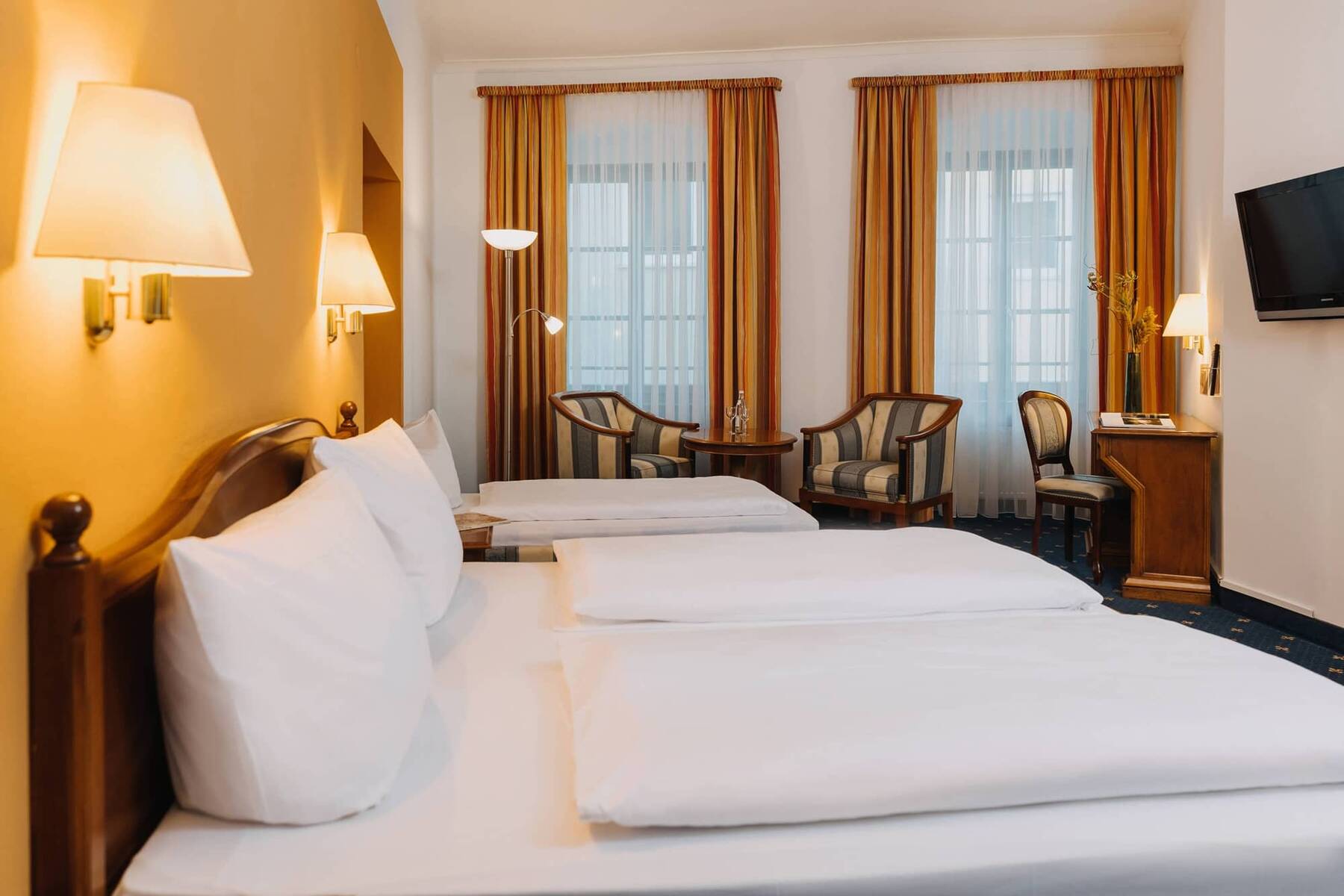 Ein einladendes Hotelzimmer mit zwei Betten, einem Sitzbereich und großen Fenstern, ideal für einen Familienurlaub.