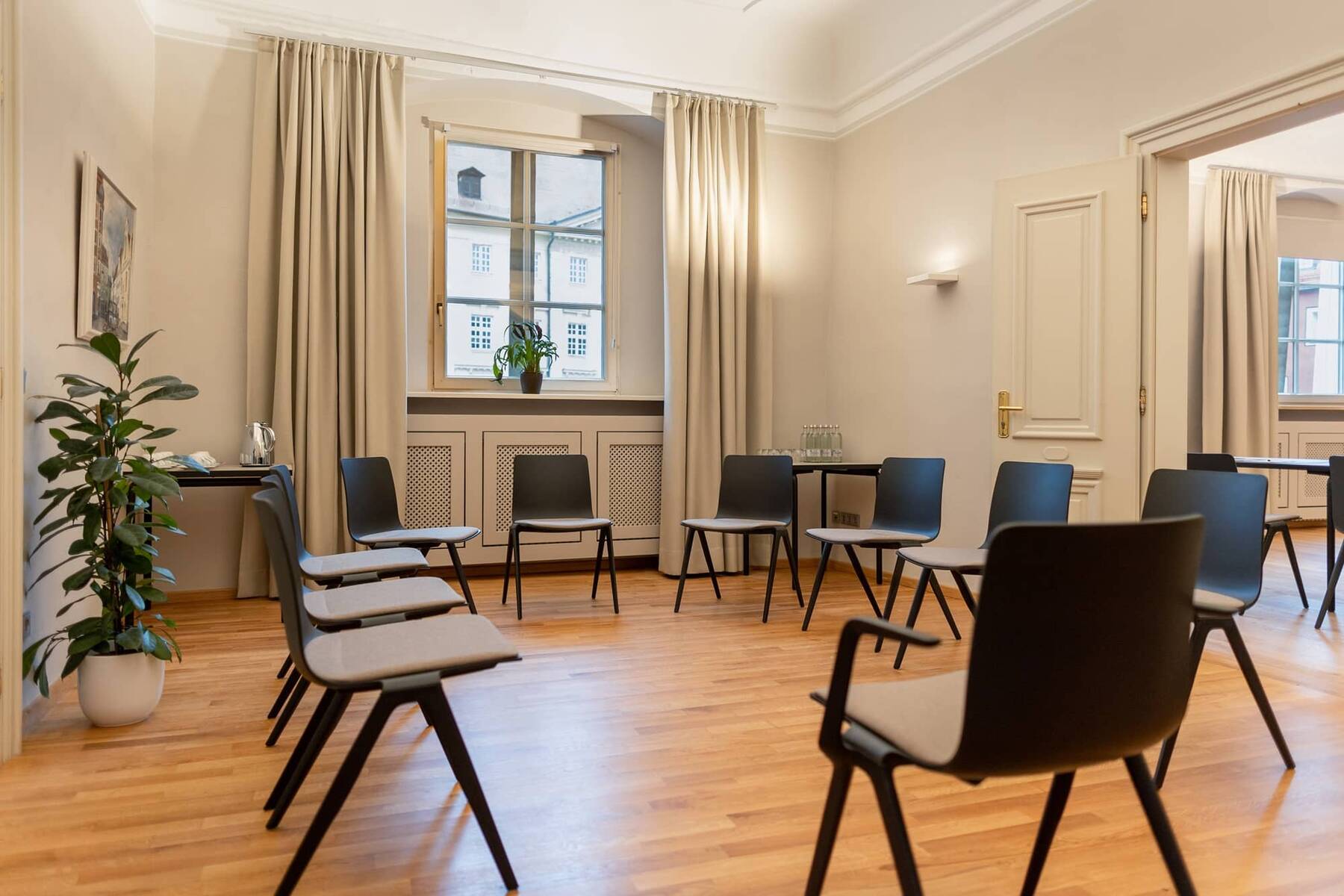 Ein moderner Seminarraum mit Stühlen, Holzfußboden und großen Fenstern, ideal für Workshops und Meetings.