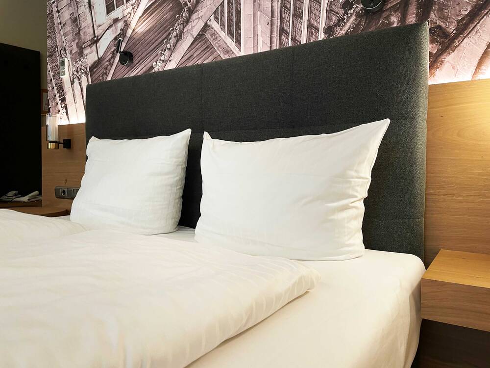 Doppelzimmer in einem modernen Hotel mit weißen Kissen und Bettwäsche, ideal für einen erholsamen Familienurlaub.