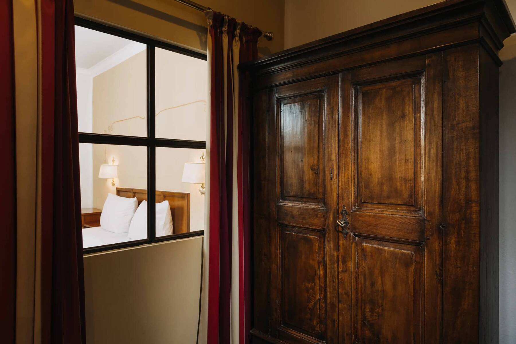 Blick auf ein stilvolles Hotelzimmer mit einem Holzschrank, einem Doppelbett und sanfter Beleuchtung, ideal für einen Familienurlaub.