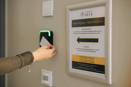 Gast öffnet den Nachteingang des Altstadthotel Arch Regensburg mit der Zimmerschlüsselkarte am Sensor – Hotel mit 24h Self-Check-in
