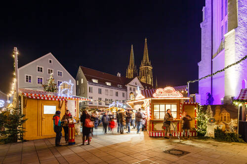 Besucher genießen den Weihnachtsmarkt in der Altstadt, umgeben von festlich beleuchteten Ständen und der beeindruckenden Architektur.