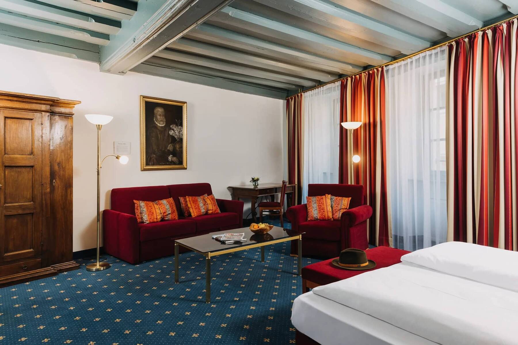Ein stilvolles Hotelzimmer mit roten Sofas, einem Tisch und einem gemütlichen Ambiente für einen entspannten Aufenthalt im Familienurlaub.