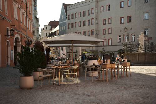 Spacious outdoor terrace of Maxim's Fine Wine Bar & Tapas on the historic Haidplatz in Regensburg in warm evening light