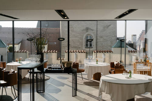 Innenansicht eines modernen Restaurants mit großen Fenstern und stilvollen Tischen, perfekt für ein romantisches Abendessen in der Stadt.