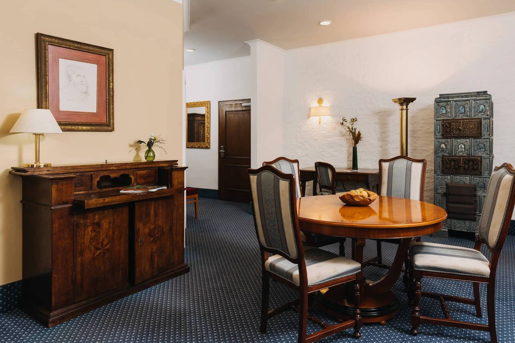 Eleganter Essbereich im Hotelzimmer, ausgestattet mit einem Holztablett, Stühlen und einem dekorativen Kamin, ideal für Familienurlaube.