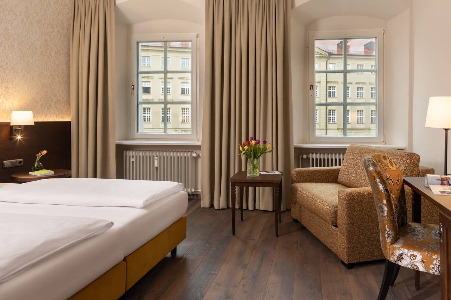 Gemütliches Zimmer im Hotel Stadtblick mit einem Doppelbett, einem Sessel und einem Tisch, ideal für einen entspannten Aufenthalt in der Altstadt.