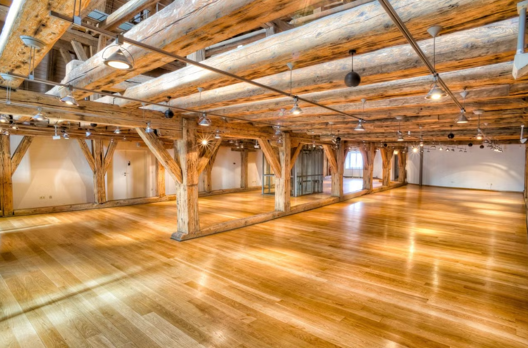 Ein lichtdurchfluteter Veranstaltungsraum mit Holzdecke und Parkettboden, ideal für Hochzeiten und Firmenfeiern.