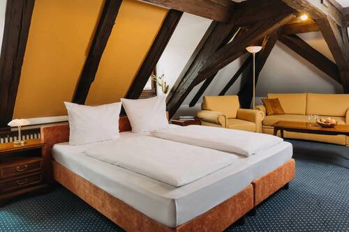 Ein komfortables Zimmer im Hotel mit einem Doppelbett, Holzverkleidung und einer gemütlichen Sitzecke für entspannte Momente.