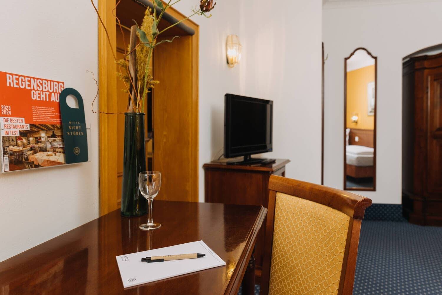 Ein stilvoll eingerichtetes Hotelzimmer mit einem Tisch, Stuhl, Fernseher und dekorativer Vase, ideal für einen entspannten Aufenthalt.