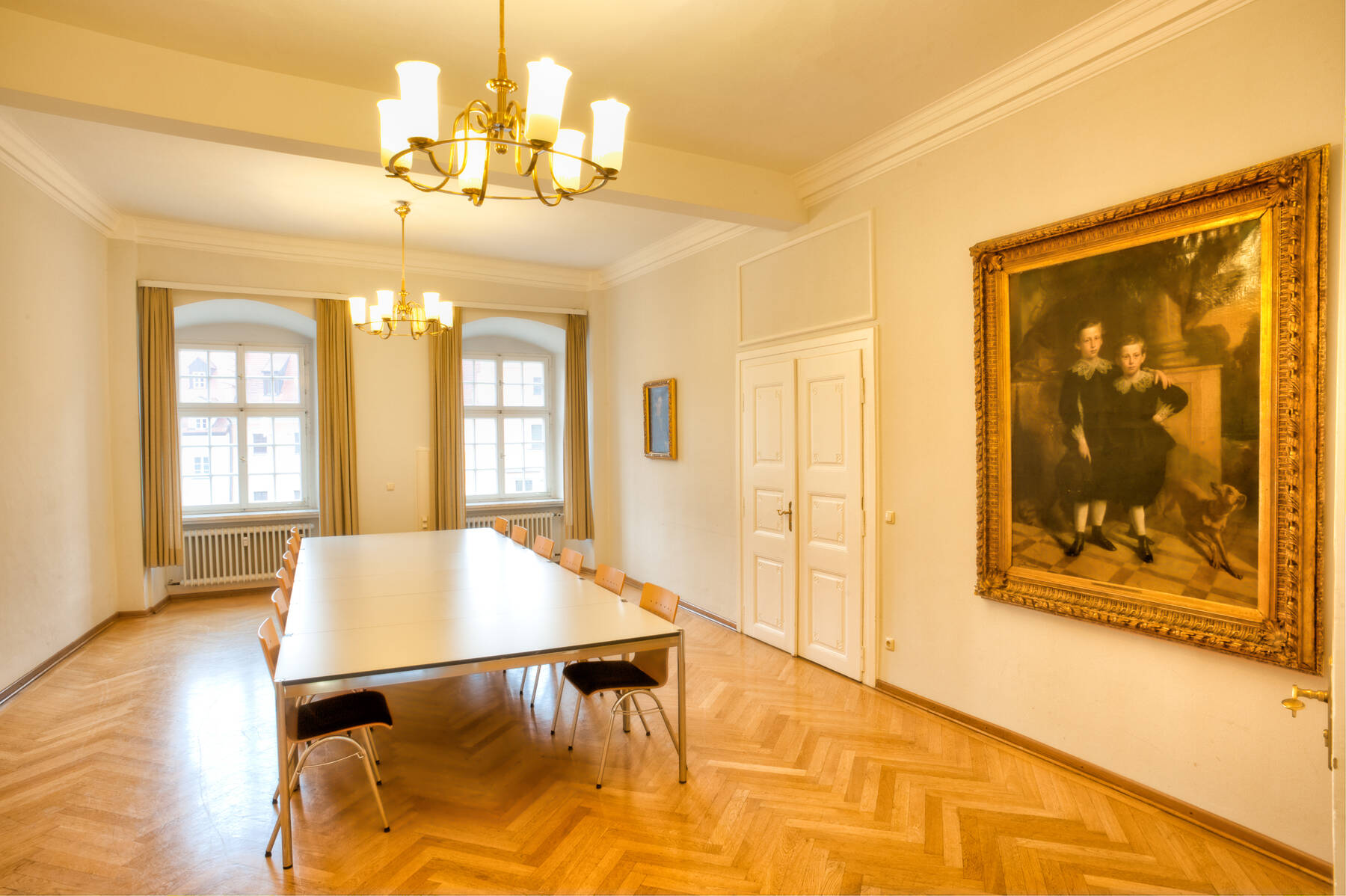 Ein heller Konferenzraum im Hotel mit einem großen Tisch, Stühlen und einem historischen Gemälde an der Wand, ideal für Meetings.