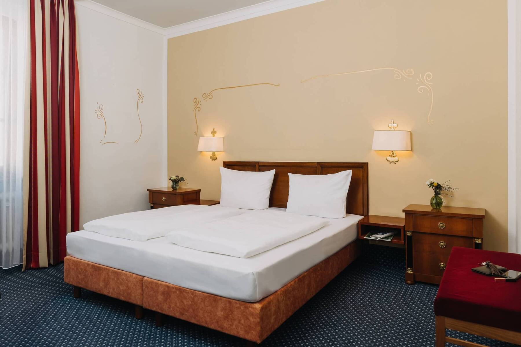 Doppelzimmer im Hotel mit zwei Betten, Nachttischen und stilvollen Lampen, ideal für einen Familienurlaub oder romantische Auszeit.