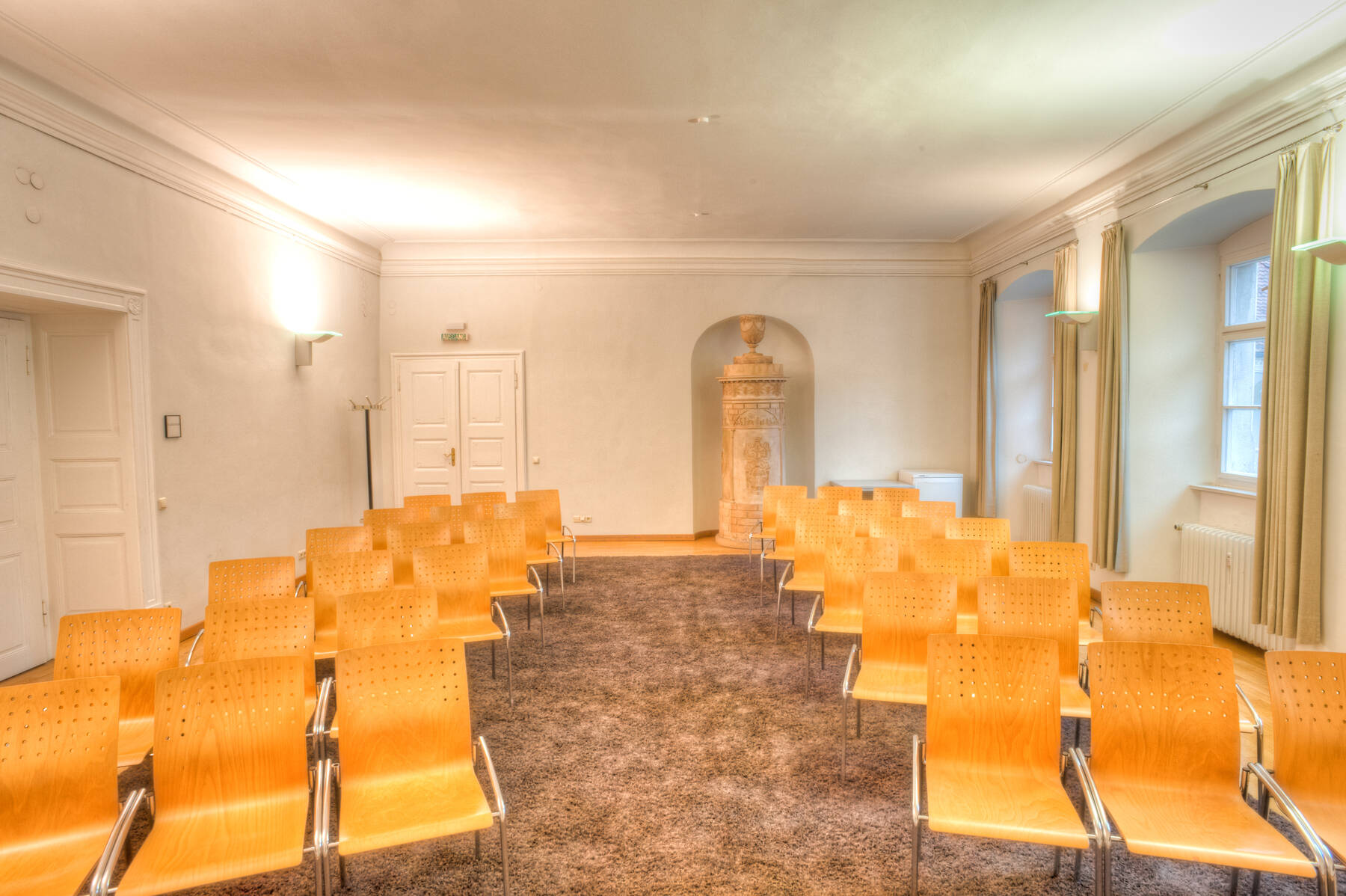 Tagungsraum mit Holzstühlen und eleganter Einrichtung, ideal für Meetings und Veranstaltungen in einem stilvollen Hotel.