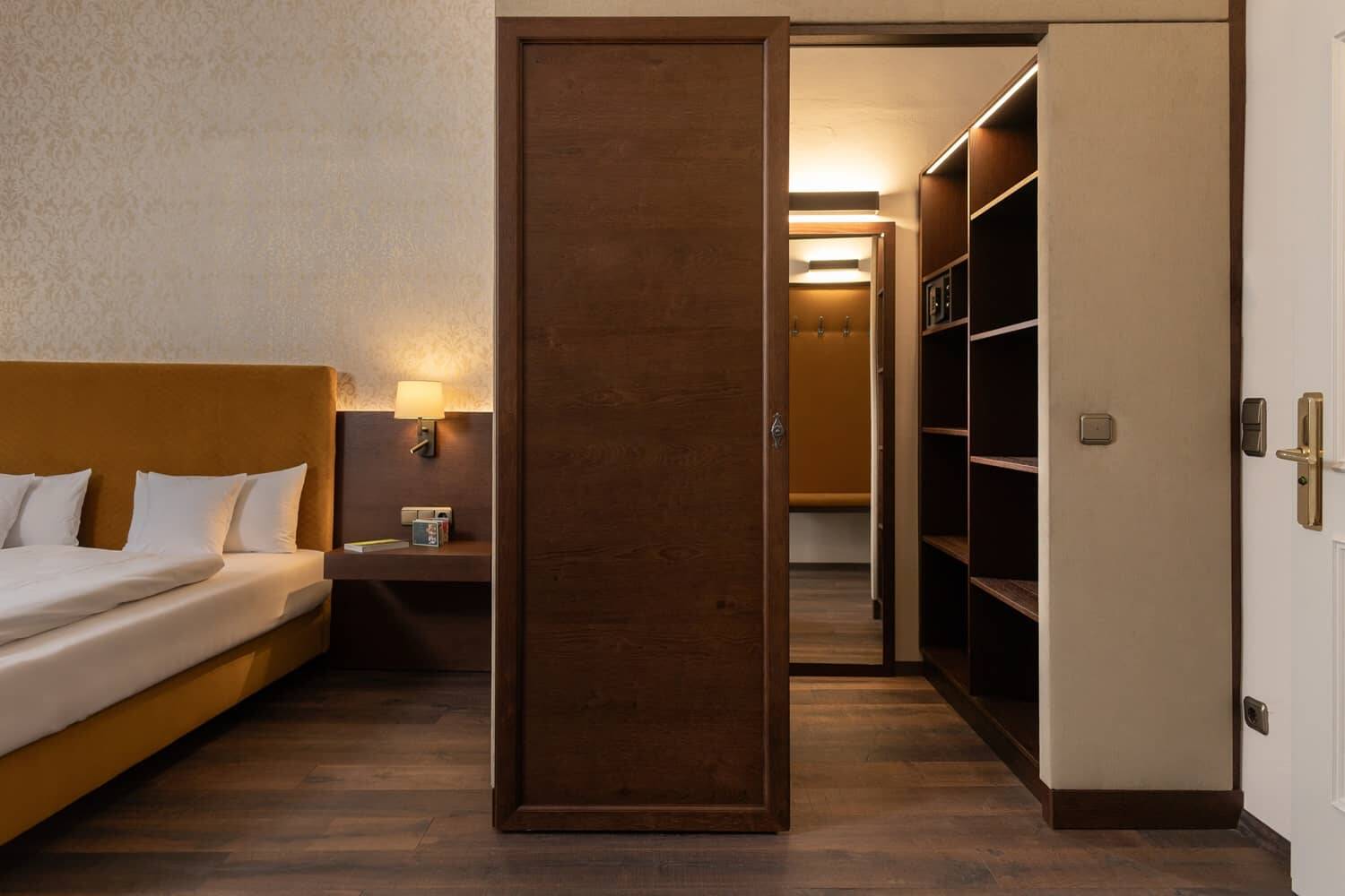 Modernes Hotelzimmer mit einem komfortablen Bett, einem Nachttisch und einem begehbaren Kleiderschrank im Hotel für Familienurlaub.