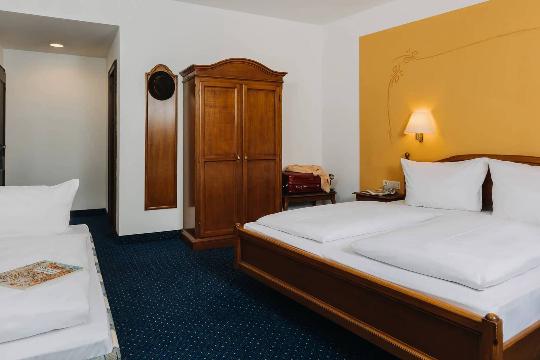 Ein stilvolles Doppelzimmer im Hotel Alpenglück mit Holzschränken und zwei Betten, ideal für einen Familienurlaub in den Bergen.