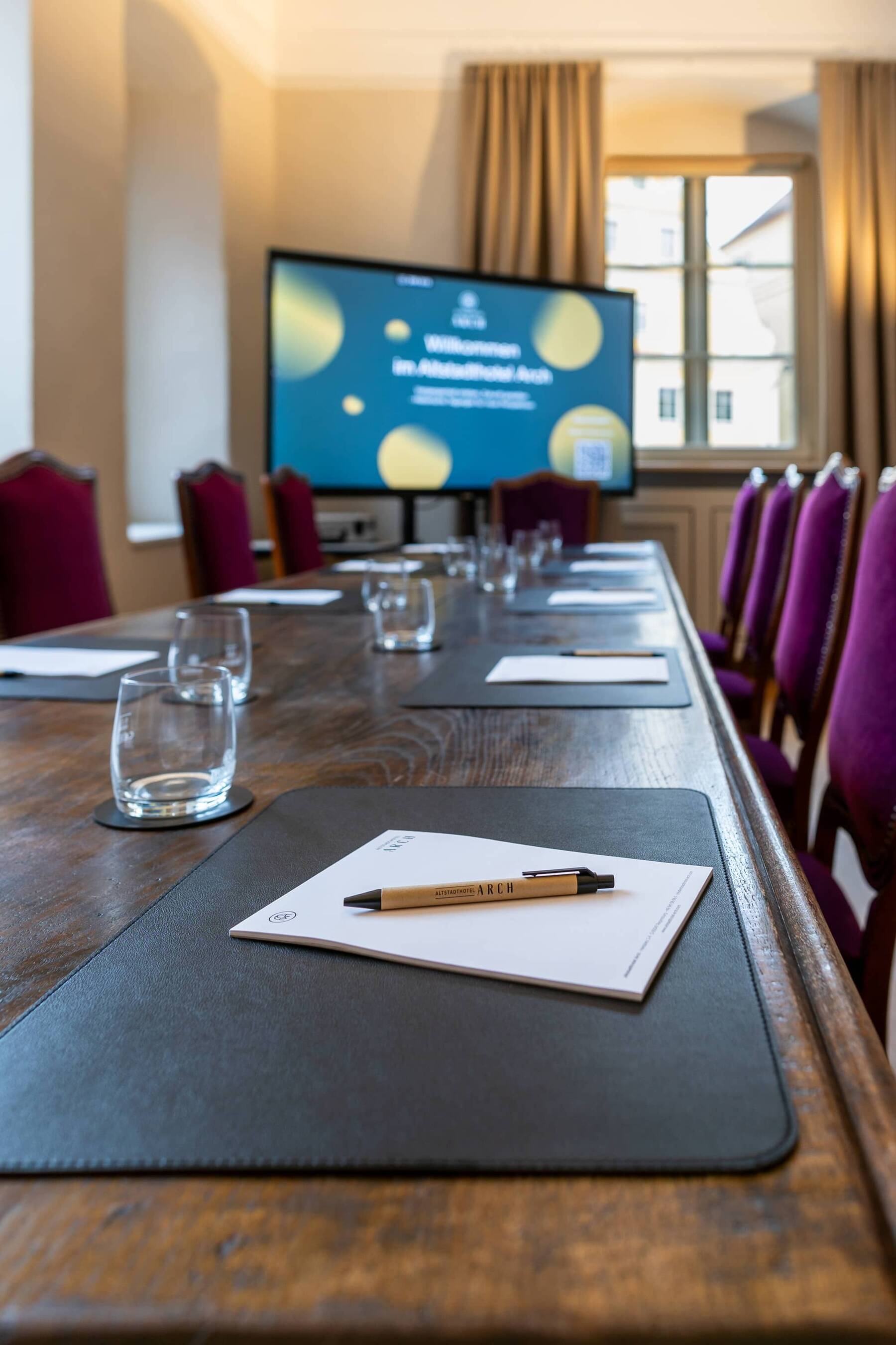 Konferenzraum im Hotel mit Holztisch, komfortablen Stühlen und einem Bildschirm für Präsentationen bei geschäftlichen Meetings.