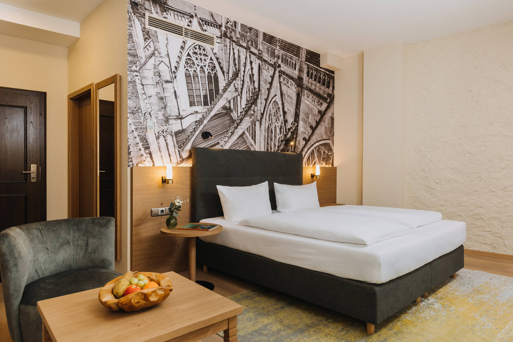 Modernes Hotelzimmer mit einem großen Bett, einer Sitzecke und einer stilvollen Wandgestaltung, ideal für einen entspannten Aufenthalt.