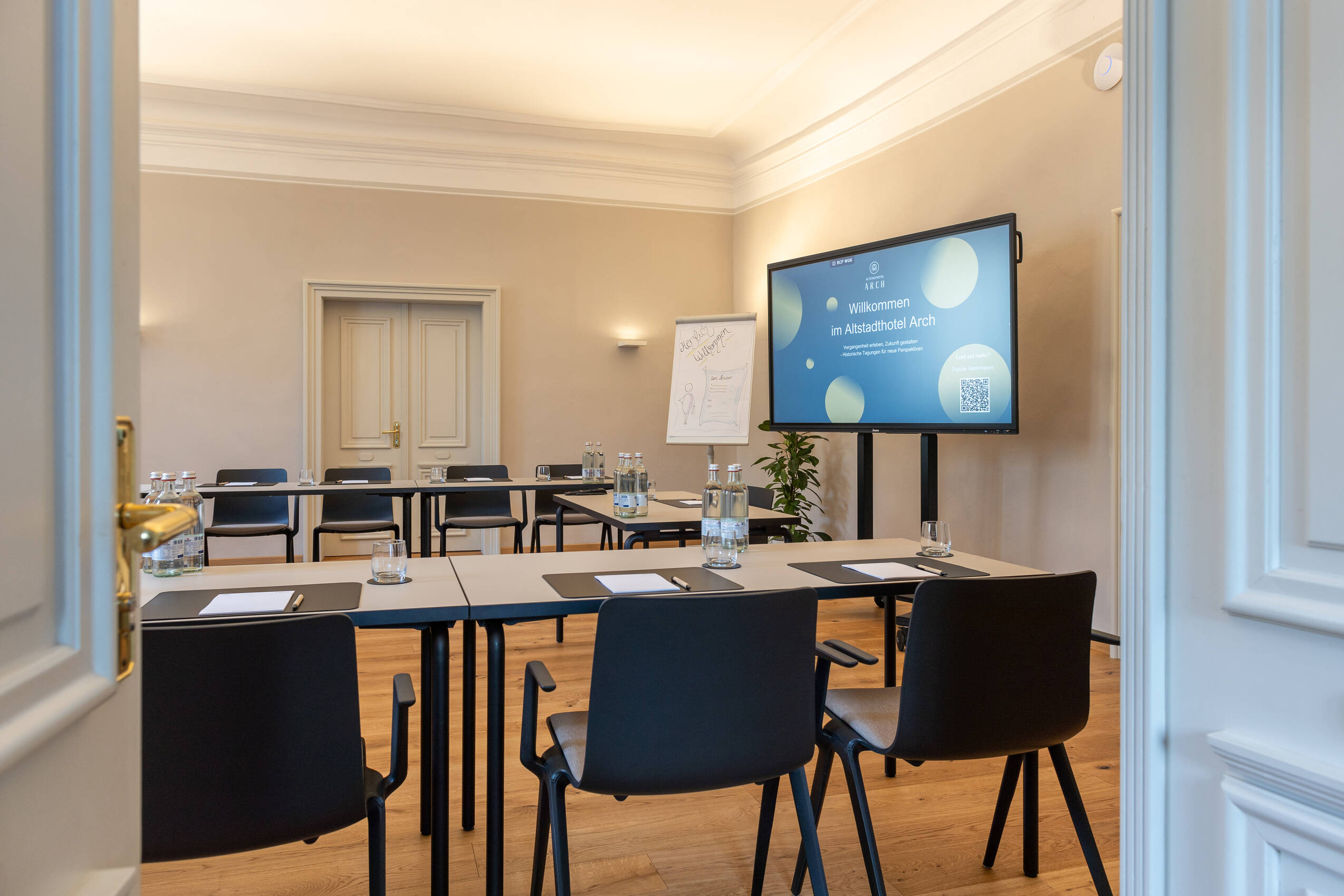 Ein Konferenzraum im Altstadthotel Arch, ausgestattet mit Tischen, Stühlen und einem großen Bildschirm für Meetings und Veranstaltungen.