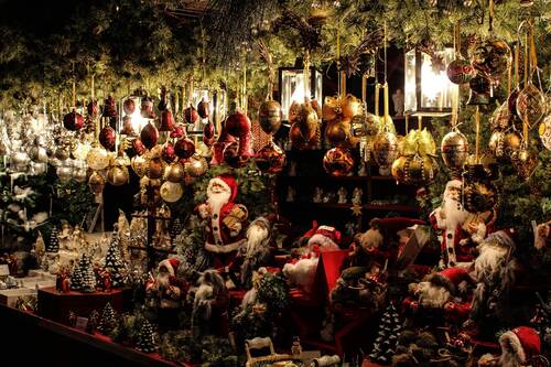 Ein festlich geschmückter Marktstand mit Weihnachtsornamenten, Figuren und Lichtern, ideal für einen besinnlichen Weihnachtsbesuch.