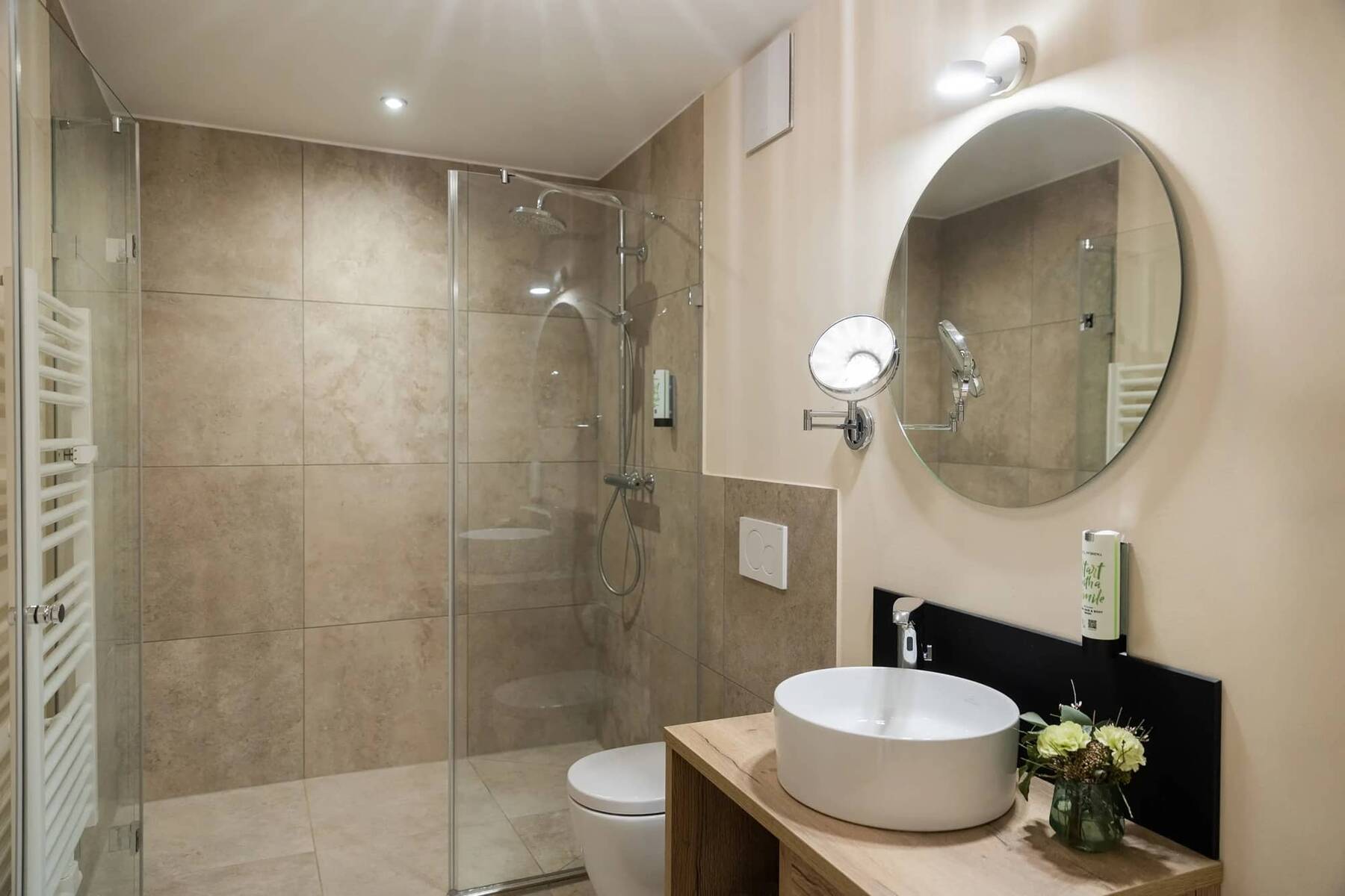 Ein modernes Badezimmer im Hotelzimmer mit Glasduschabtrennung, Waschbecken und eleganten Fliesen für einen komfortablen Aufenthalt.