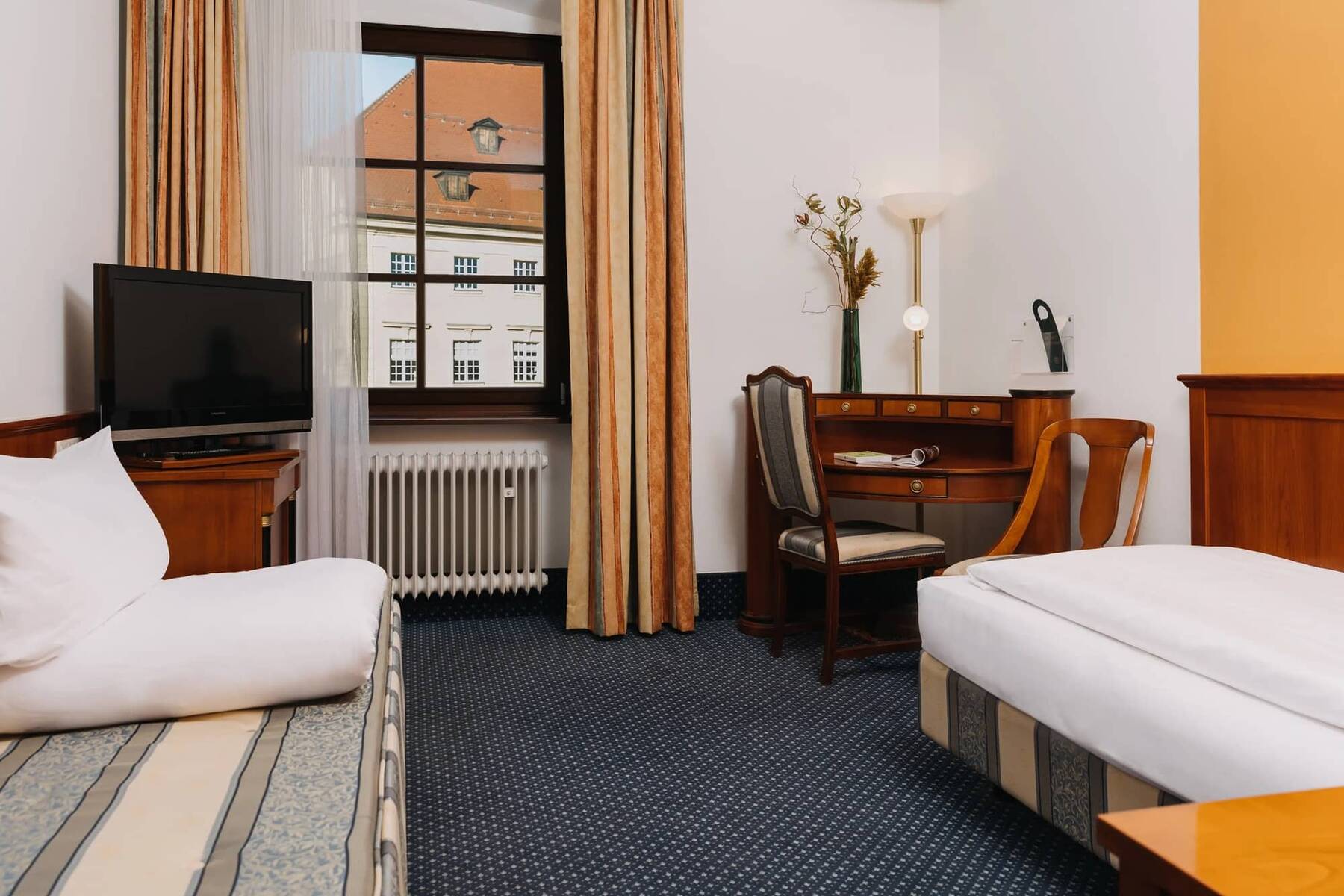 Innenansicht eines Hotelzimmers mit TV, Schreibtisch und gemütlicher Einrichtung, ideal für den Familienurlaub in der Region.