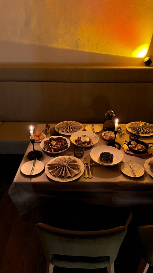Generously set table with a variety of tapas dishes by candlelight at Maxim's Fine Wine Bar & Tapas, Altstadthotel Arch Regensburg