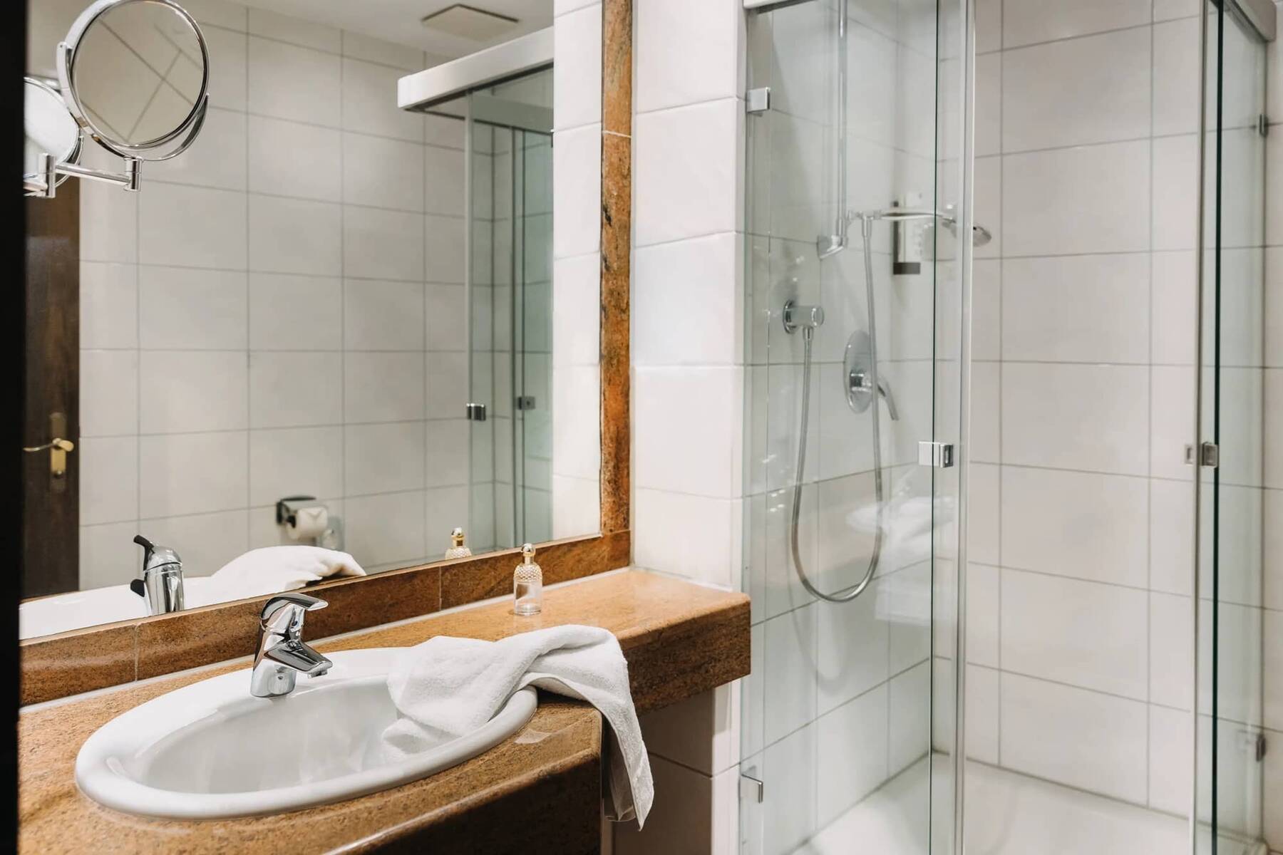 Badezimmer im Hotel Alpenglück mit Dusche, Waschbecken und stilvollem Design, ideal für einen entspannten Aufenthalt im Familienurlaub.