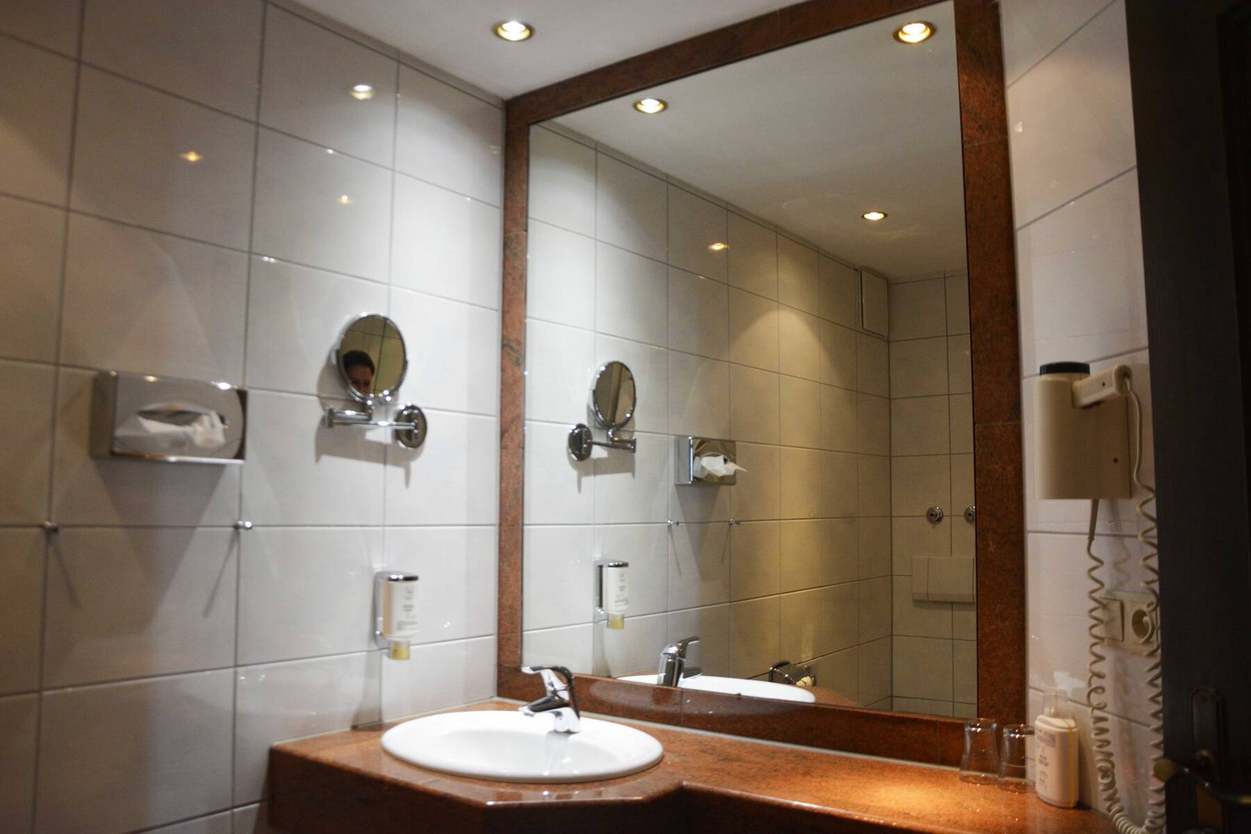 Badezimmer im Hotel mit Waschbecken, großem Spiegel und modernen Armaturen, ideal für einen komfortablen Aufenthalt.
